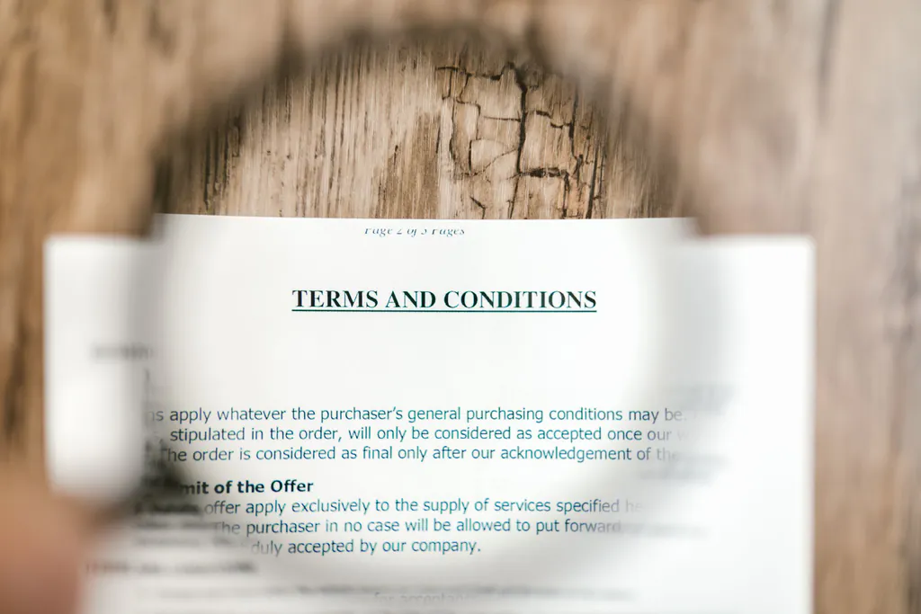 Magnifying glass held over a printed terms and conditions page from a vendor contract